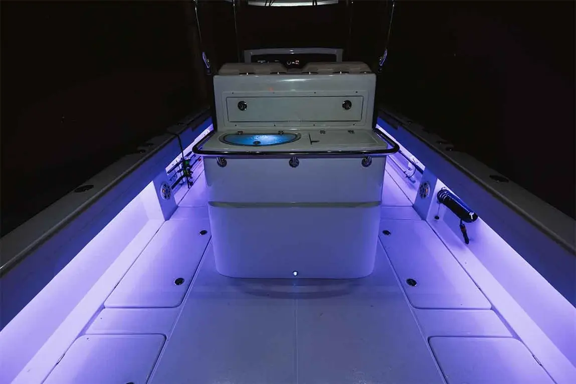 Interior view of a boat featuring a lit storage compartment with a blue display, surrounded by ambient purple lighting.